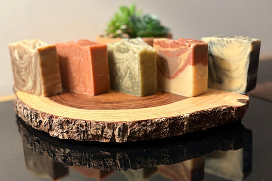 Wooden soap dish with five rectangular soap bars on a reflective surface.